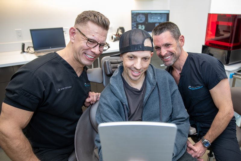 nathan a dental implant patient smilingintomirror_with dr cory ryan and dr hoffman