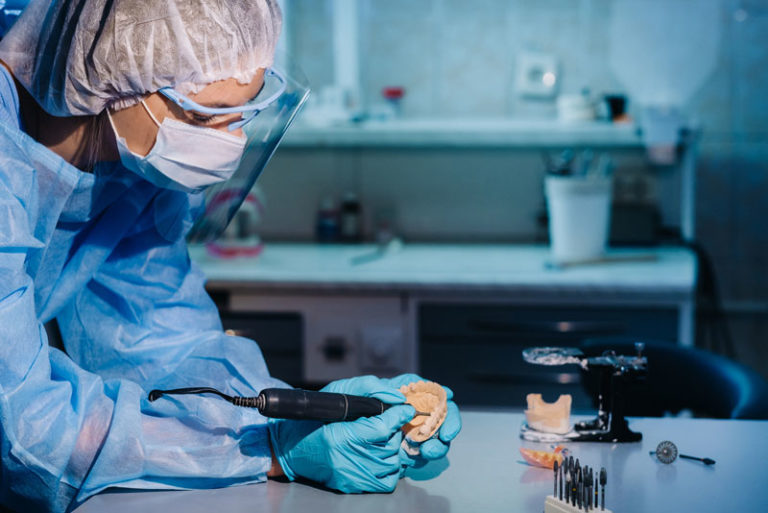 a dental implant dentist milling a full mouth dental implant prosthetic in a dental lab.